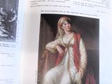 un livre ouvert sur lequel figure l'image d'une femme vêtue d'une robe blanche et d'une cape rouge