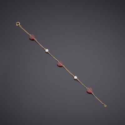 a close up of a gold bracelet with red and white beads