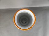 a white and orange cup sitting on top of a white table