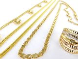 several different types of gold necklaces and bracelets on a white surface