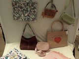 several purses and handbags are displayed on a table in front of a white backdrop