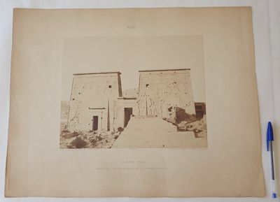 an old photograph of a stone building with a blue pen next to it