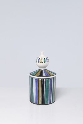 an image of a small jar with a lid on a white surface