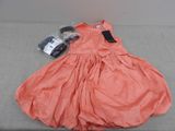 an orange dress with a tag on it sitting on a couch