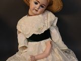 a doll that is sitting on the ground with a hat on