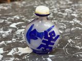 une bouteille en verre bleue et blanche posée sur une table