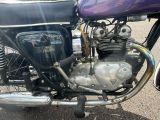 a purple motorcycle parked in a parking lot next to other cars