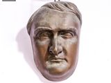 une tête d'homme en bronze sur un mur blanc