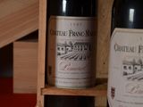 two bottles of wine sitting on a wooden shelf