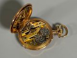 a gold pocket watch sitting on a white surface