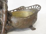 a bronze statue of a woman with a basket on it