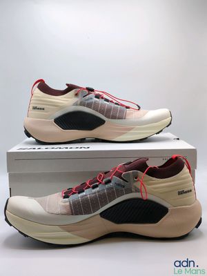 une paire de baskets blanches et rouges posée sur une boîte