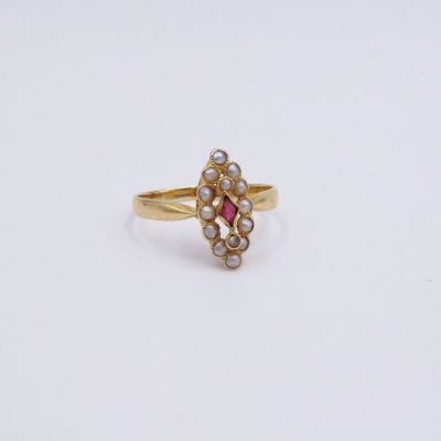 a close up of a gold ring with pearls and a pink stone