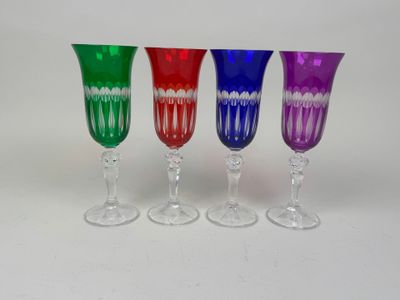 four wine glasses are lined up in a row on a white surface