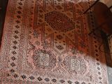 a rug on the floor with a chair in the corner