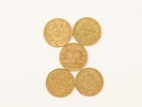quatre pièces d'or superposées sur une surface blanche