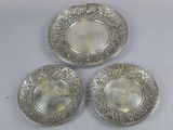 three silver plated dishes sitting on a white surface
