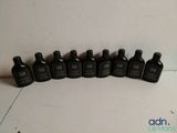 six bottles of black liquid lined up on a white surface
