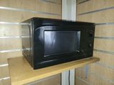 a black microwave sitting on top of a wooden shelf