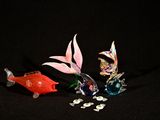 trois figurines de poissons en verre posées sur une surface noire