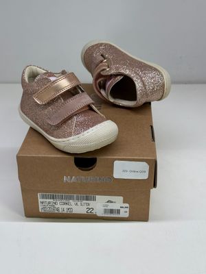 des chaussures de petite fille dans une boîte posée sur une surface blanche