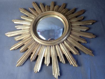 a gold starburst mirror on a blue cloth