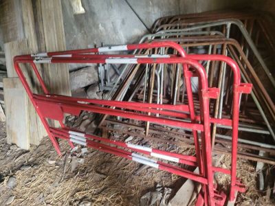 un cadre de lit en métal rouge dans une grange, avec du foin par terre