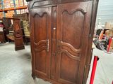 une armoire ancienne dans un entrepôt, avec de nombreux meubles en arrière-plan