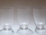 six verres vides sont alignés sur une surface blanche