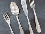 four forks and two spoons on a black table