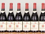 six bottles of wine are lined up on a wooden table