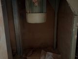 a toilet in the corner of a room with a sheet of paper on the floor