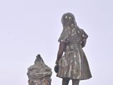 a statue of a little girl and a pot on a plate
