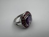 a close up of a ring with a purple stone surrounded by red stones