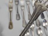 a lot of silver spoons and forks hanging on the wall