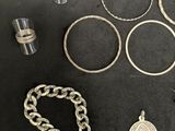 some silver rings and other silver jewelry on a black surface