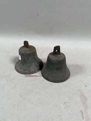 une paire de cloches anciennes posées sur un support blanc, accompagnées d'une étiquette