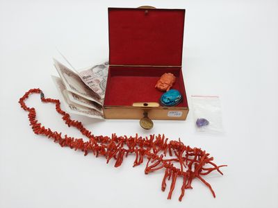 une boîte rouge contenant un tas de perles rouges et une perle rouge