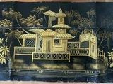 une boîte peinte en noir et or, sur laquelle est représenté un bâtiment