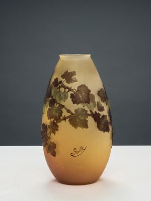 un vase jaune orné de feuilles, posé sur une table