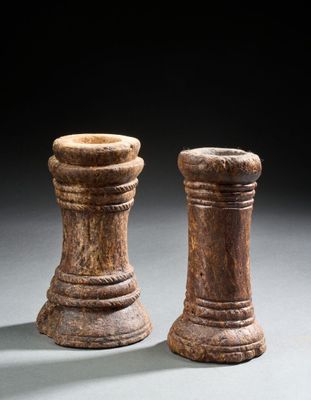une paire de bougeoirs en bois sculpté posés sur un support gris