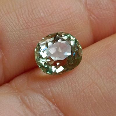 un gros plan sur la main d'une personne tenant un diamant vert et blanc