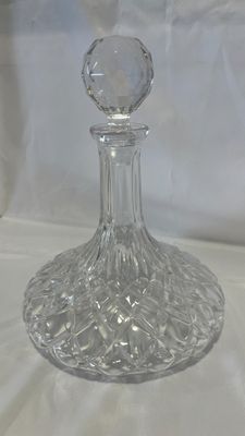 une carafe en verre transparent posée sur une nappe blanche, sur fond blanc