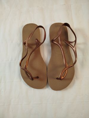 une paire de sandales pour femme posée sur un lit recouvert d'un drap blanc