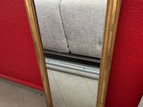 gold framed mirror on the floor next to a couch in a living room