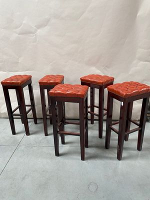quatre tabourets en cuir rouge posés sur un sol carrelé