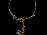 a close up of a gold bracelet with a blue bead