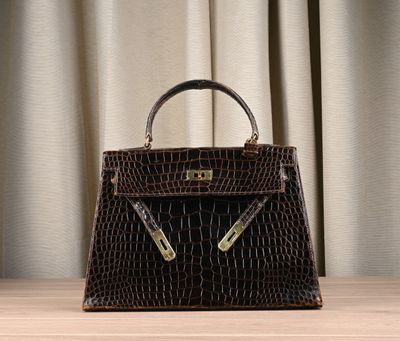 the brown crocodile skin handbag is sitting on a wooden table