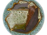 une assiette bleue ornée d'un motif marron et vert