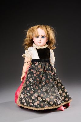 an antique porcelain doll of a woman in a black and pink dress